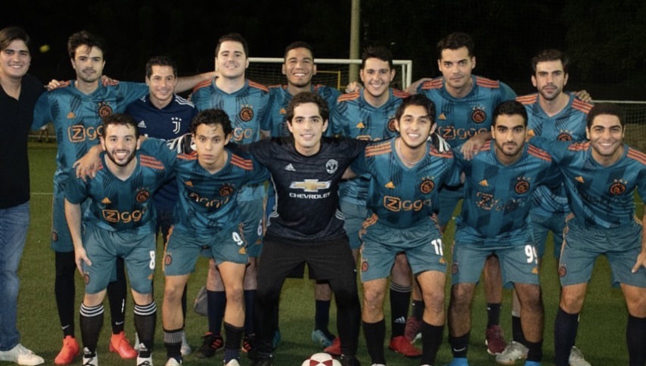 A group of young men in soccer uniforms huddle together before a soccer game.